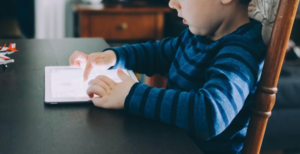 Free Image of Young child engrossed in a tablet inside a cozy home setting 
