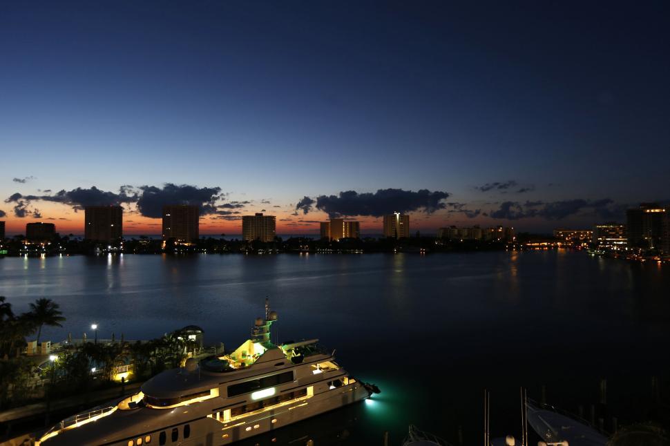 Free Image of Luxurious yacht docked at sunset with city skyline in background 