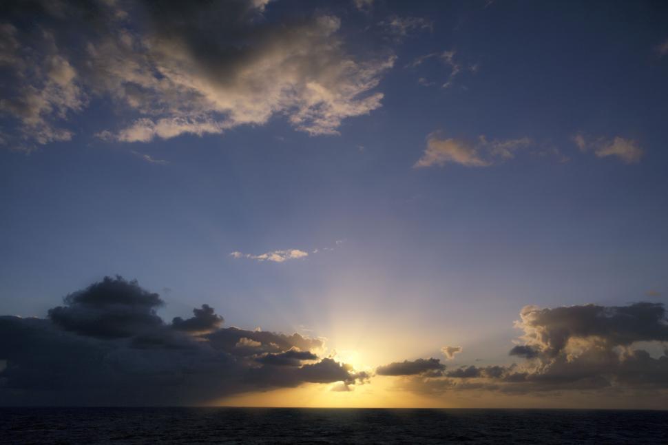 Free Image of Magnificent sunrise over ocean with sunbeams piercing through clouds 