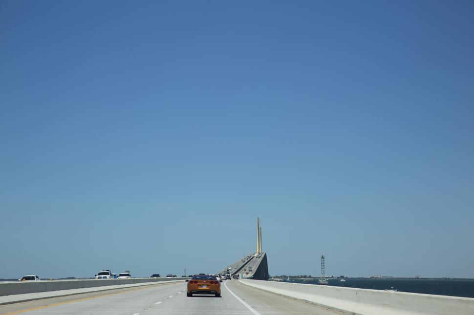 Free Image of Modern bridge under clear blue sky with cars driving across 