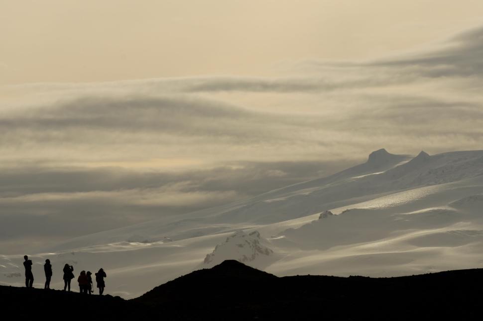 Free Image of Hikers silhouetted against a vast mountainous expanse at sunset, 