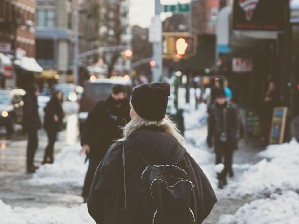 Free Image of Person walking on snowy city street wearing a black beanie 