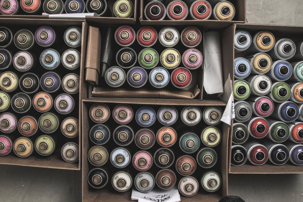 Free Image of Assortment of colorful spray paint cans stacked in boxes 