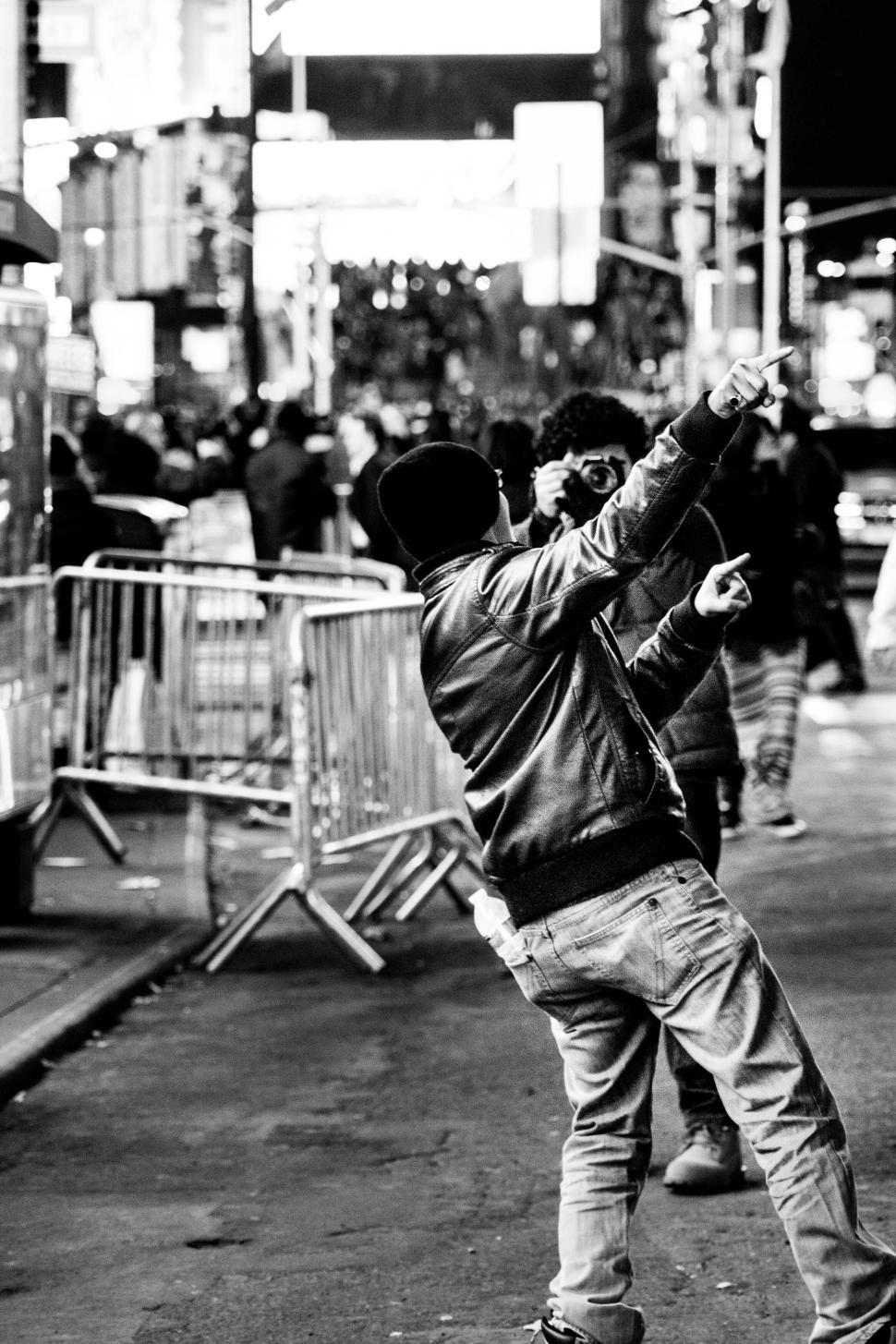Free Image of Black-and-white shot of a person pointing playfully in a busy street. 
