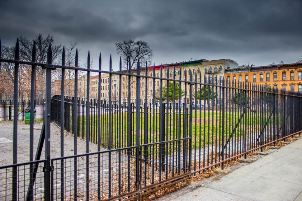 Free Image of Gated park view with overcast skies and buildings in the background. 
