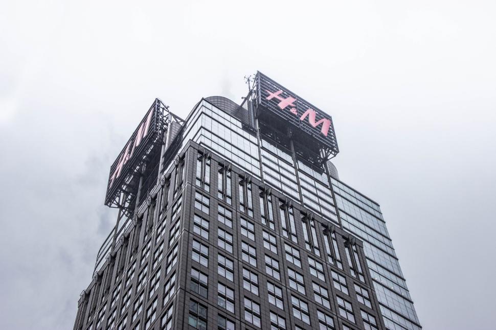 Free Image of Modern skyscraper with H&ampM sign under a cloudy and foggy sky. 