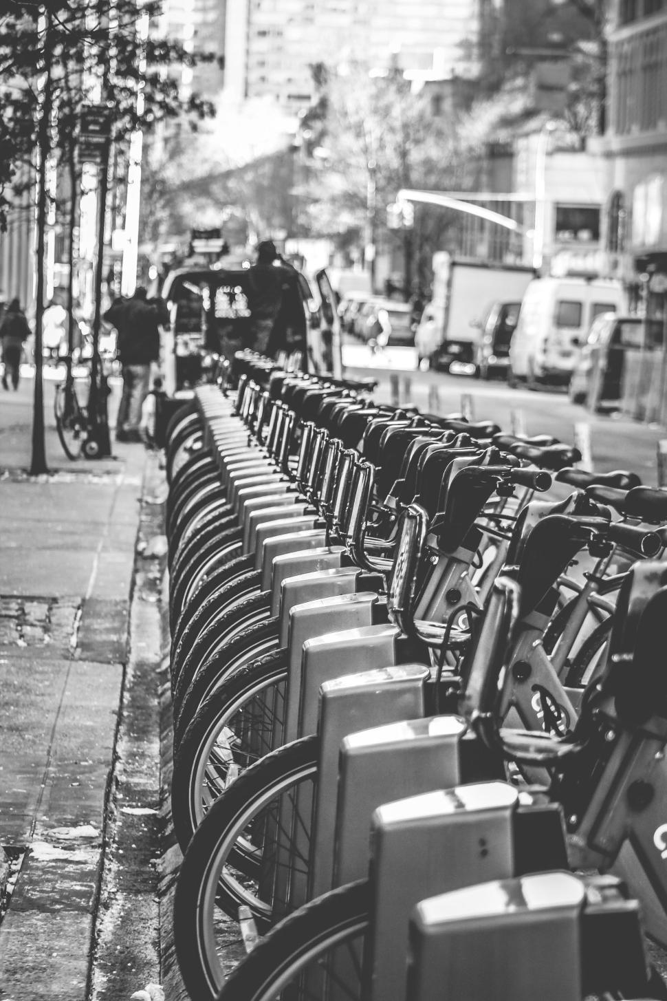 Free Image of Row of bicycles at a bike-sharing station on a busy city sidewalk. 