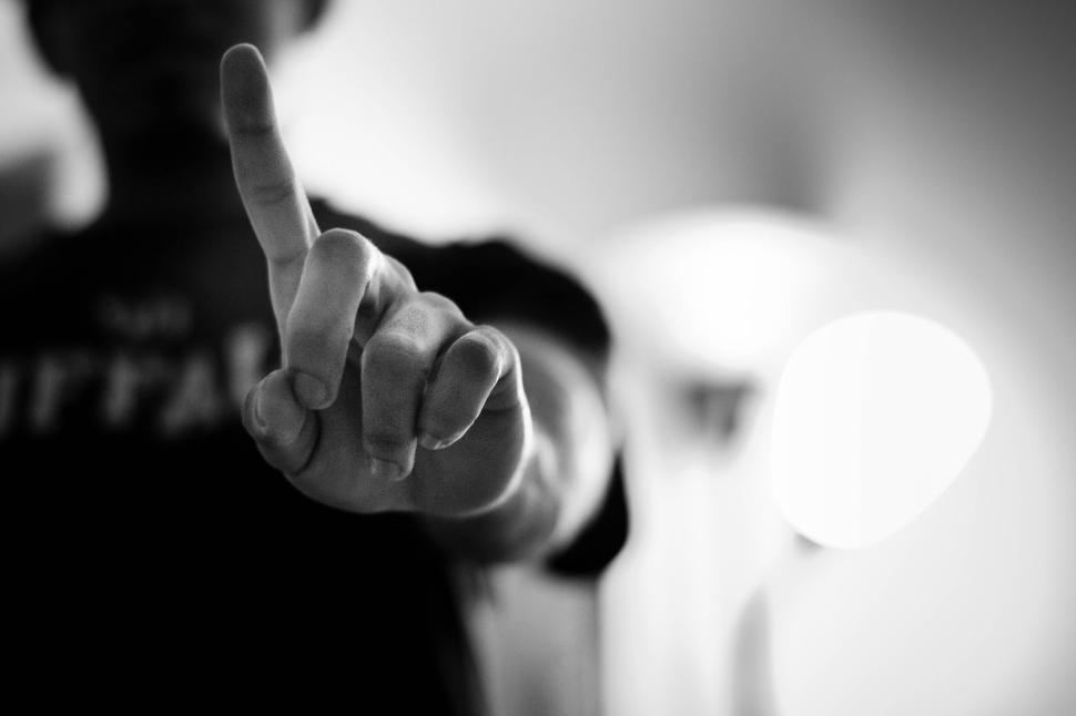 Free Image of Close-up of a person’s hand with a pointed finger in black and white. 