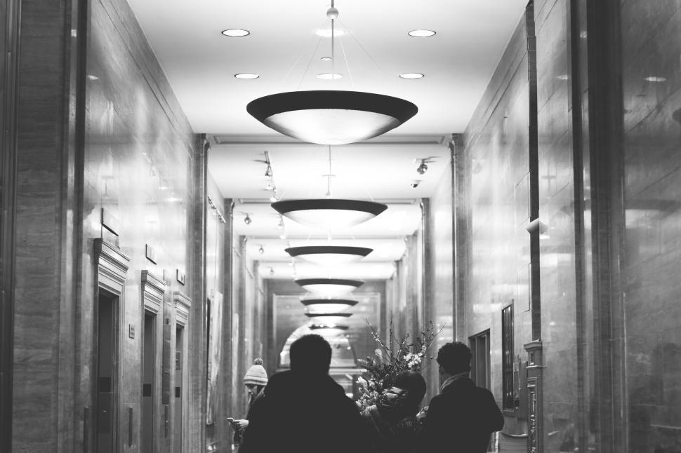 Free Image of Interior hallway with people walking under decorative hanging lights. 