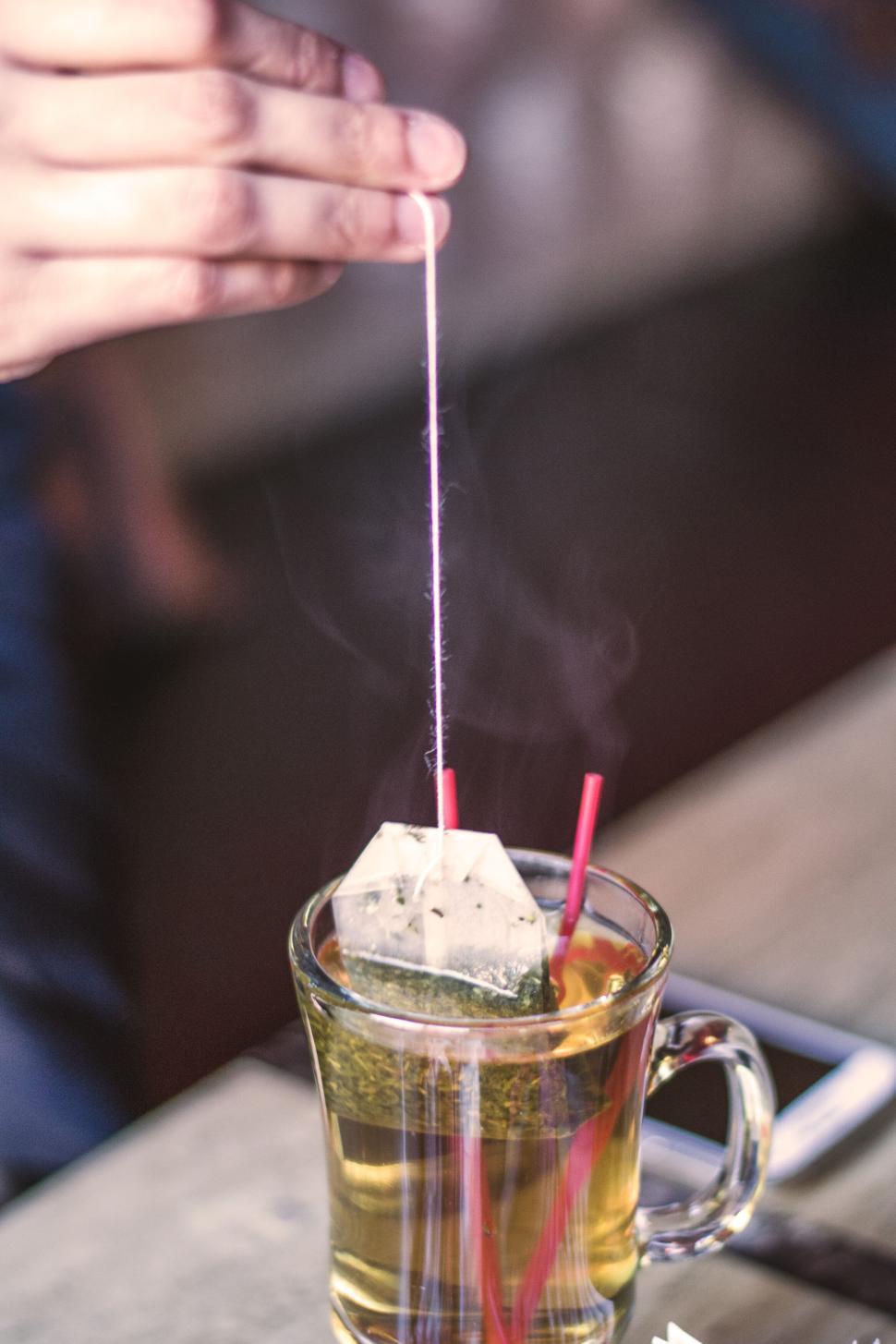 Free Image of Person brewing tea by dipping tea bag in a glass cup of hot water 