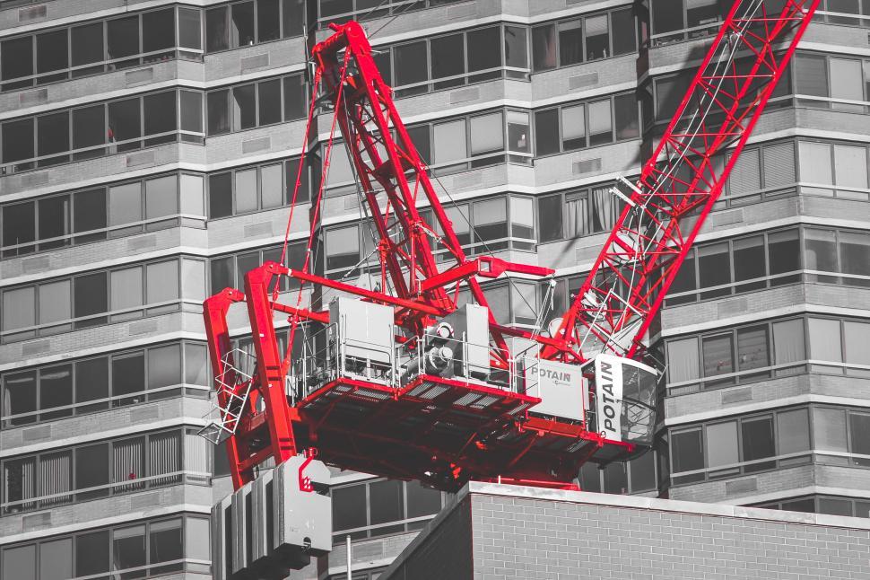Free Image of Red construction crane on the top of a building in city construction 