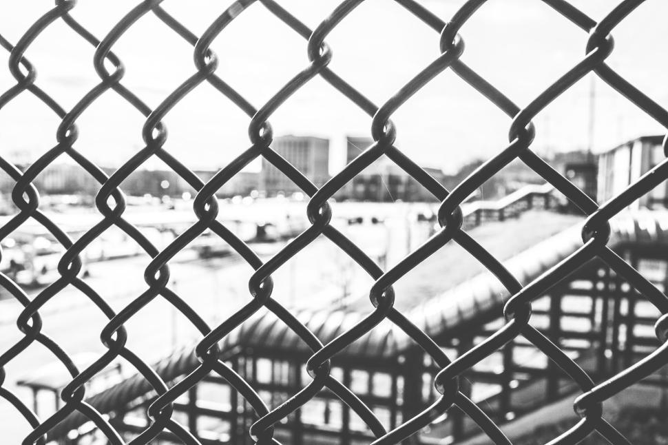 Free Image of Chain link fence with blurred urban landscape in background 