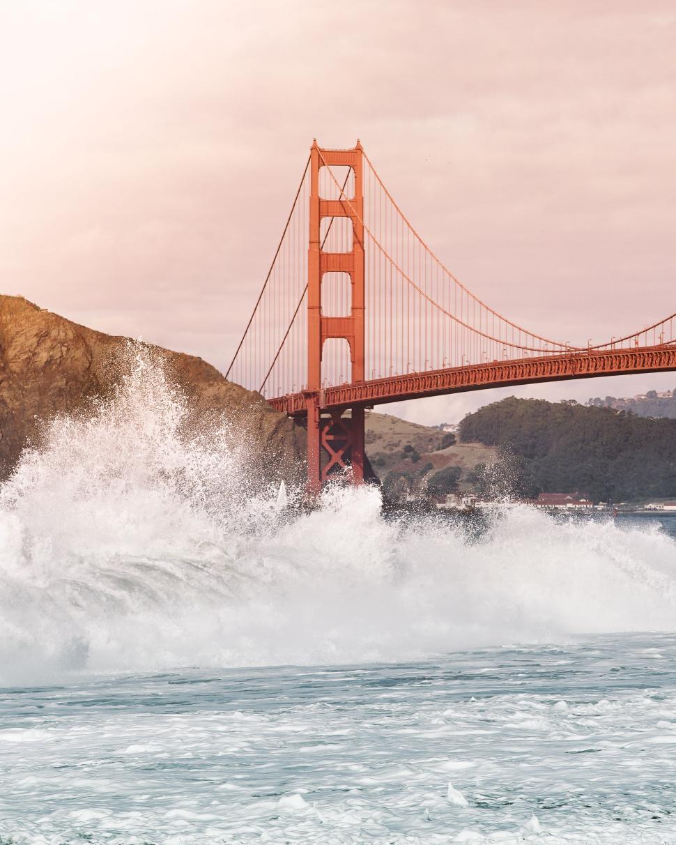 Free Image of Waves crashing near the iconic Golden Gate Bridge at sunset 
