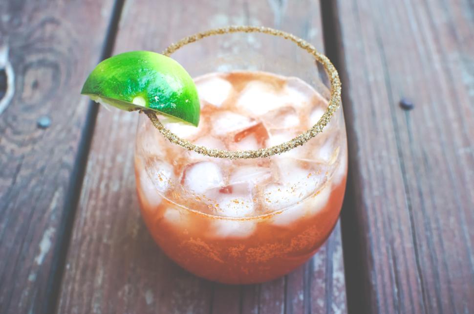 Free Image of A cocktail with lime on a wooden table, garnished with salt rim. 