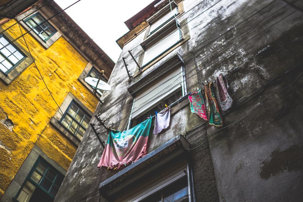 Free Image of Colorful laundry hanging outside old rustic buildings in an alley. 