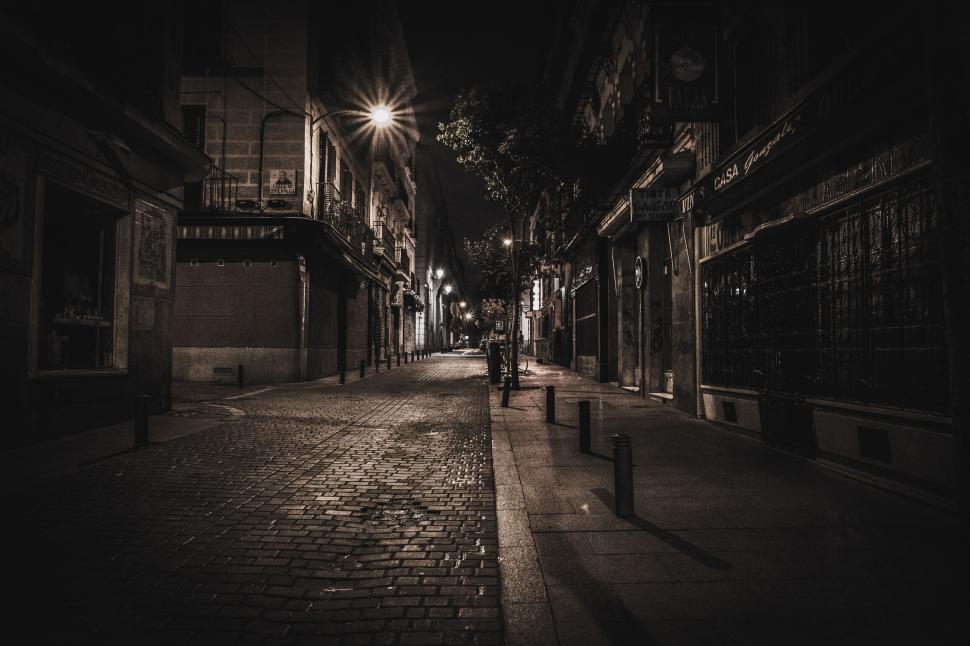 Free Image of Empty cobblestone street illuminated by street lights at night. 