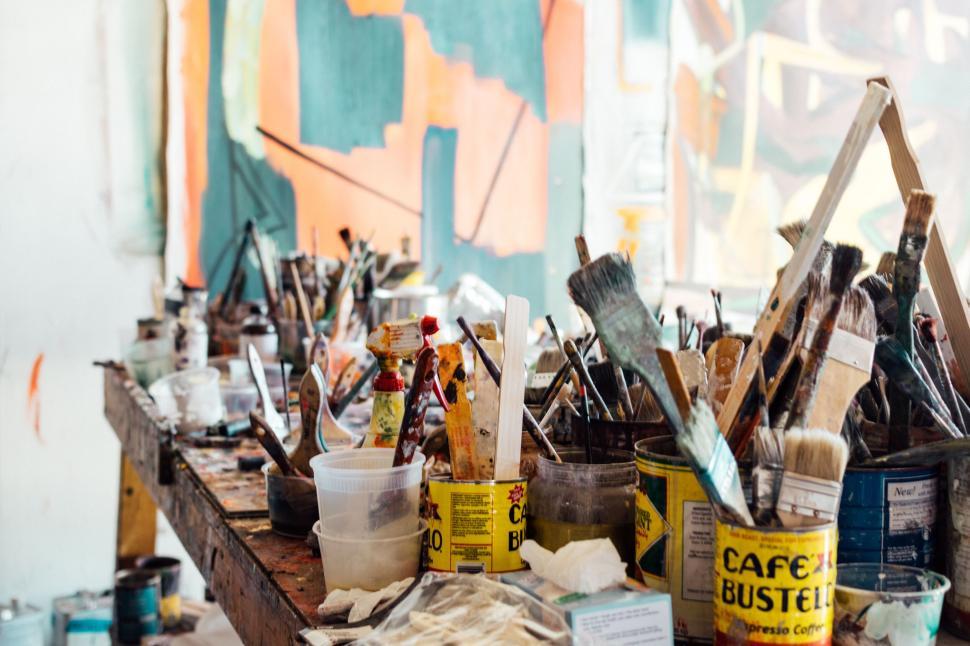 Free Image of Artists  workspace filled with paint brushes and supplies 