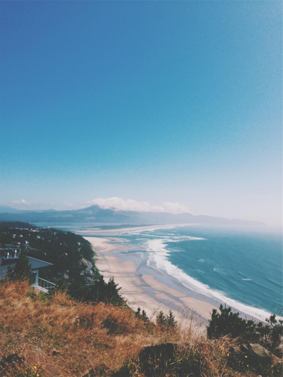 Free Image of Coastal landscape with expansive beach and distant mountain views. 