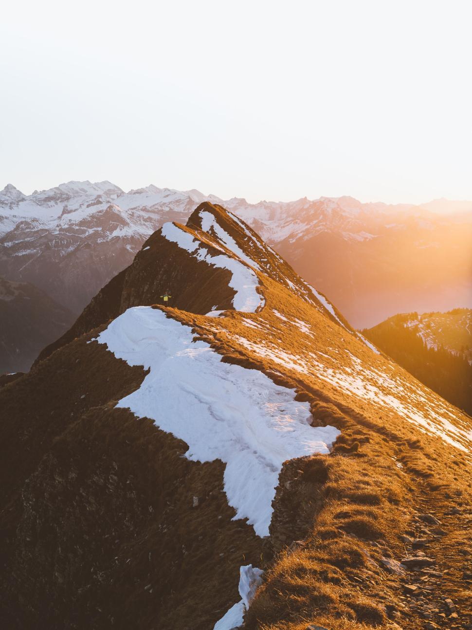 Free Image of Snow-covered mountain ridge bathed in golden sunset light. 