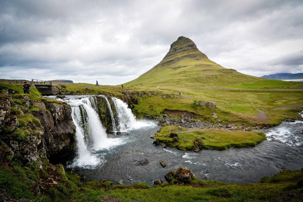 Free Image of Picturesque landscape featuring a waterfall and a grassy hill. 