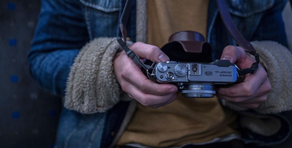 Free Image of Person holding a vintage camera with a denim jacket and shearling cuffs. 