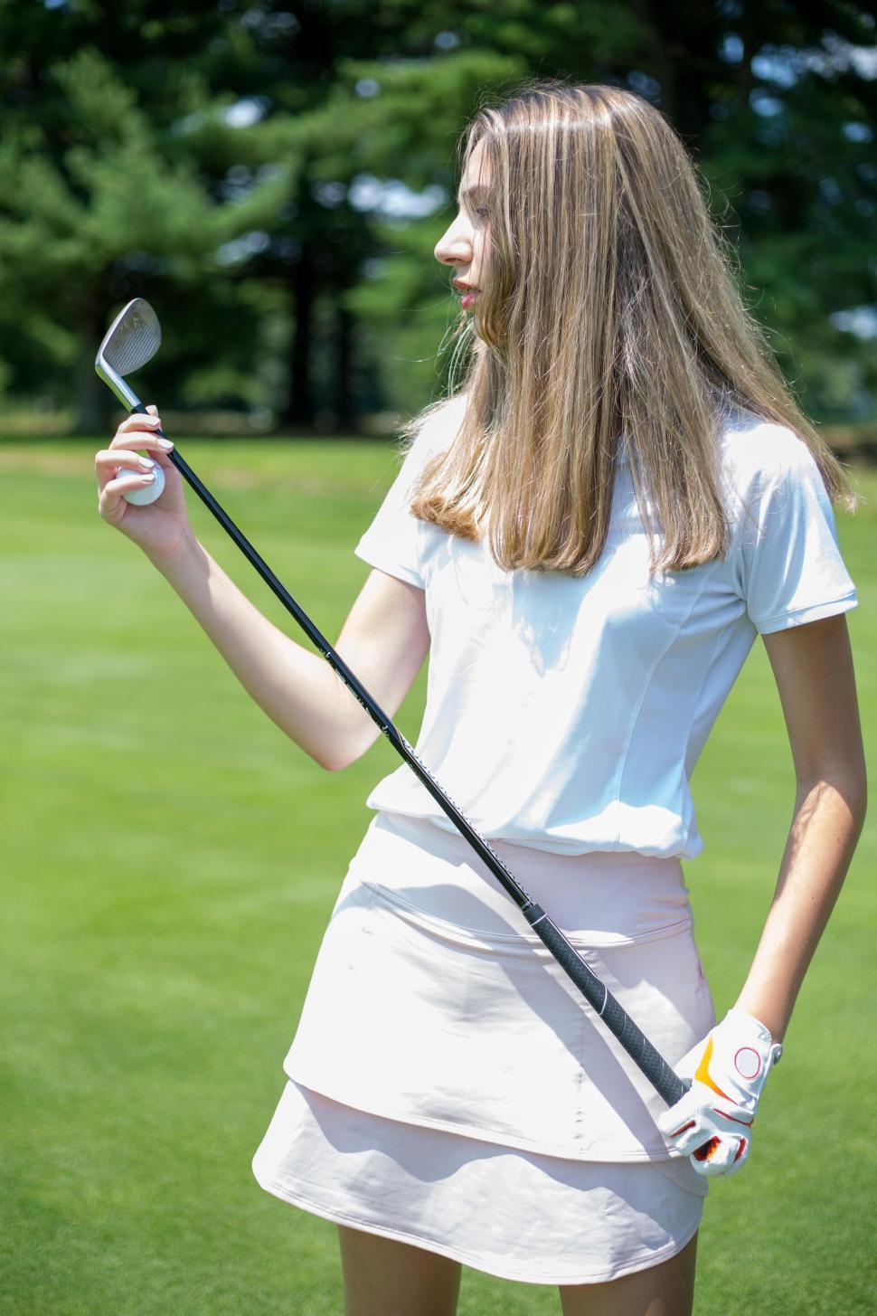 Free Image of Female Golfer Holding a Golf Club with Green Course Background 