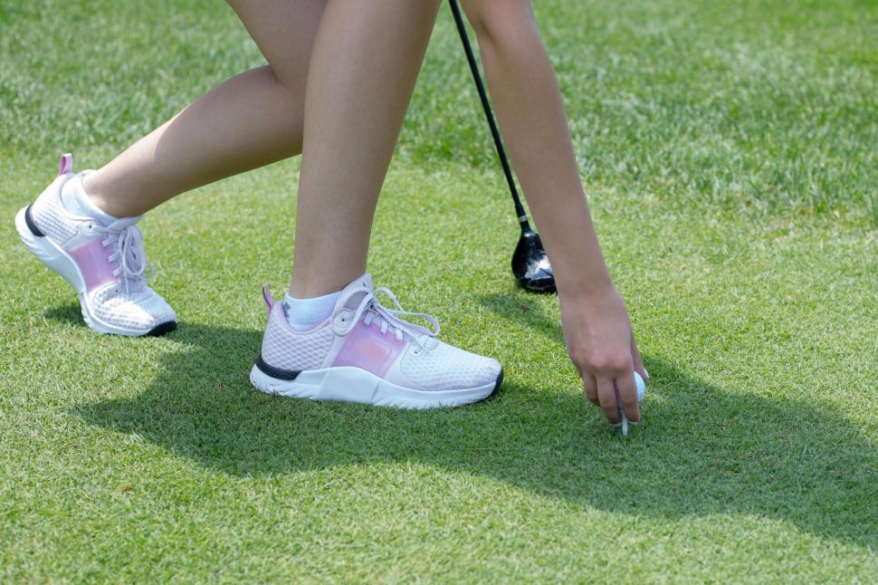 Free Image of Female Golfer Bending to Place Tee on Lush Green Golf Course 