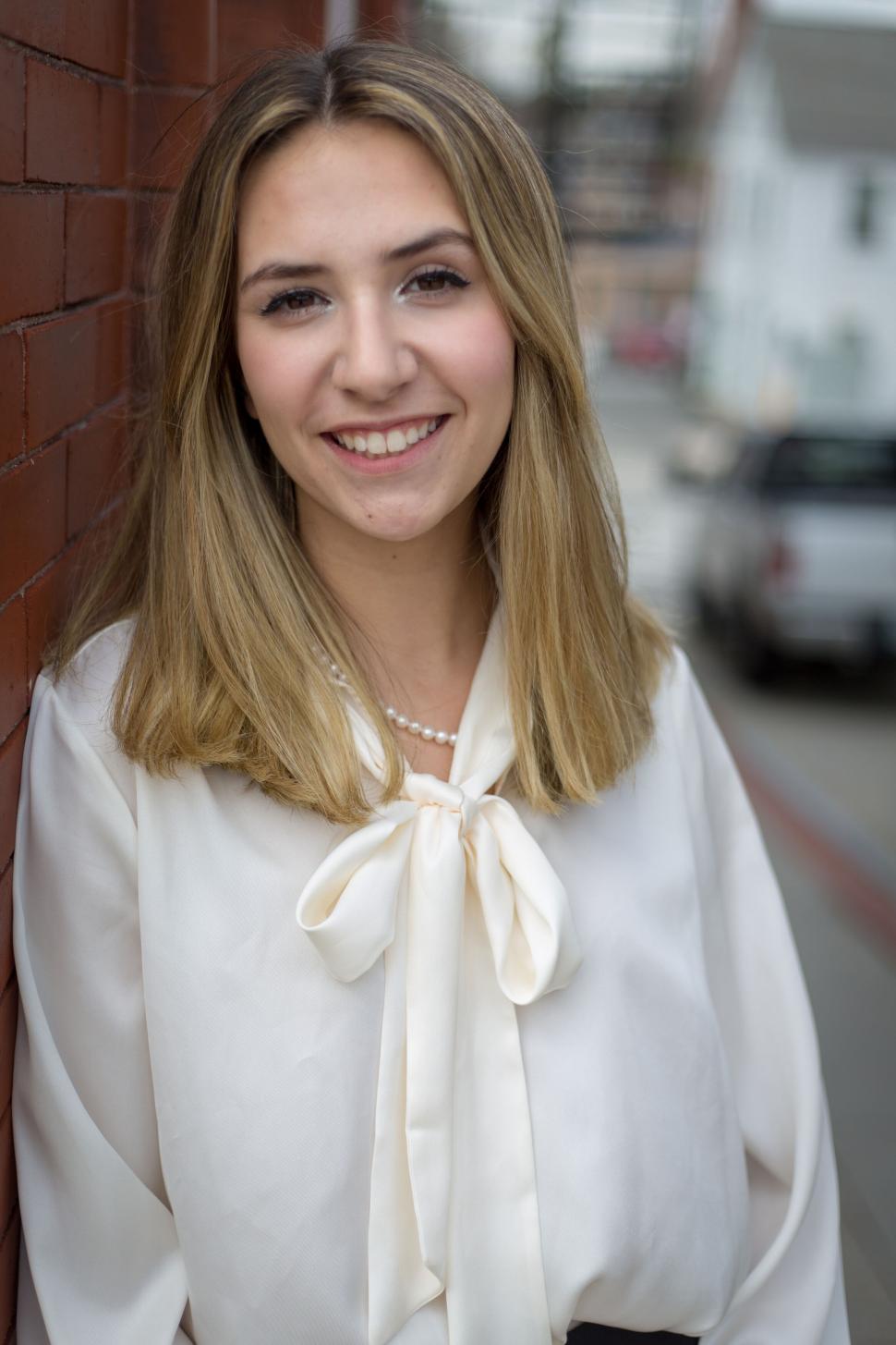 Free Image of Young woman smiling confidently wearing white blouse outdoors 