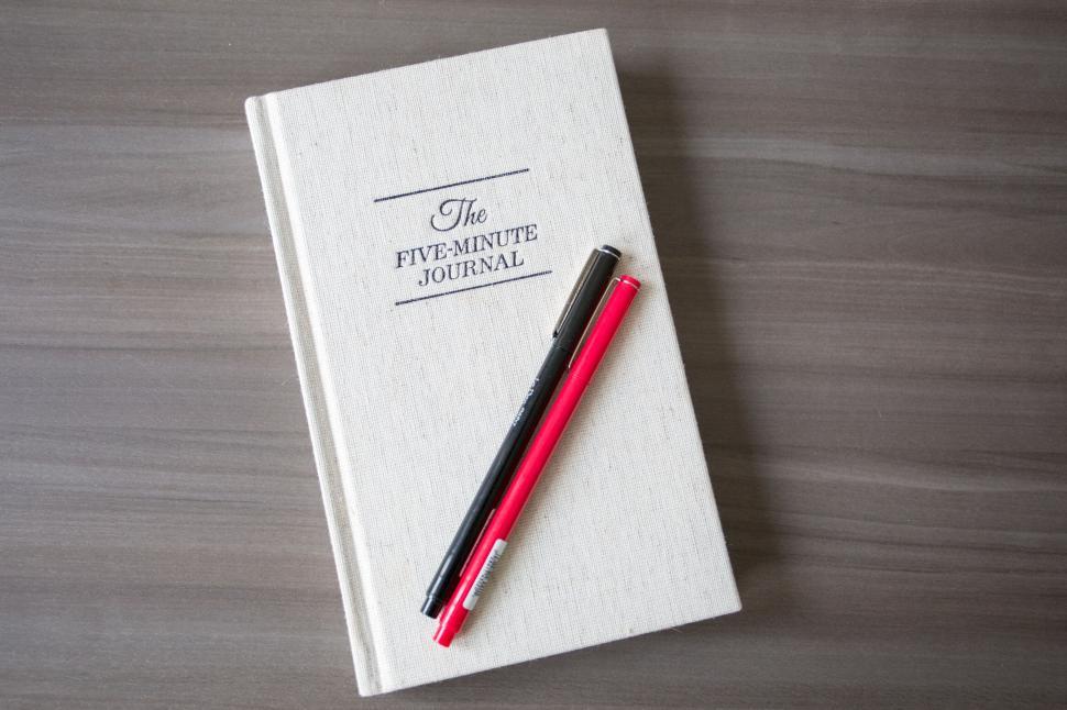 Free Image of The Five-Minute Journal Lying on Wooden Surface with Two Pens 