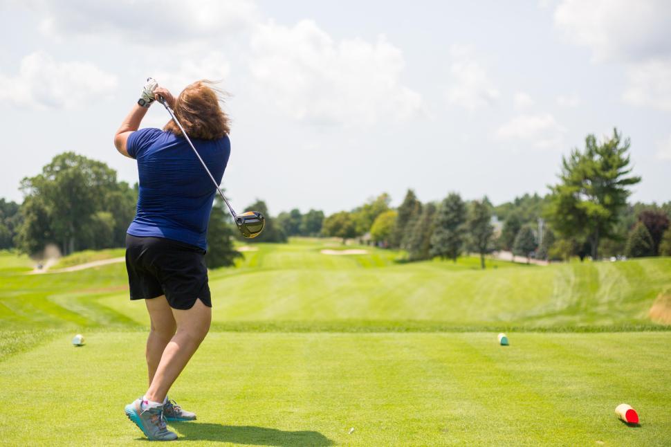 Free Image of Golfer in blue shirt, taking a powerful swing on green course. 