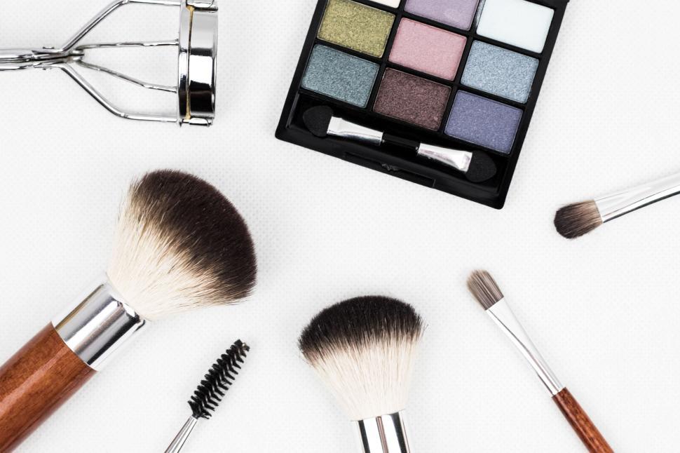 Free Image of Makeup tools and colorful palette arranged on a white background. 