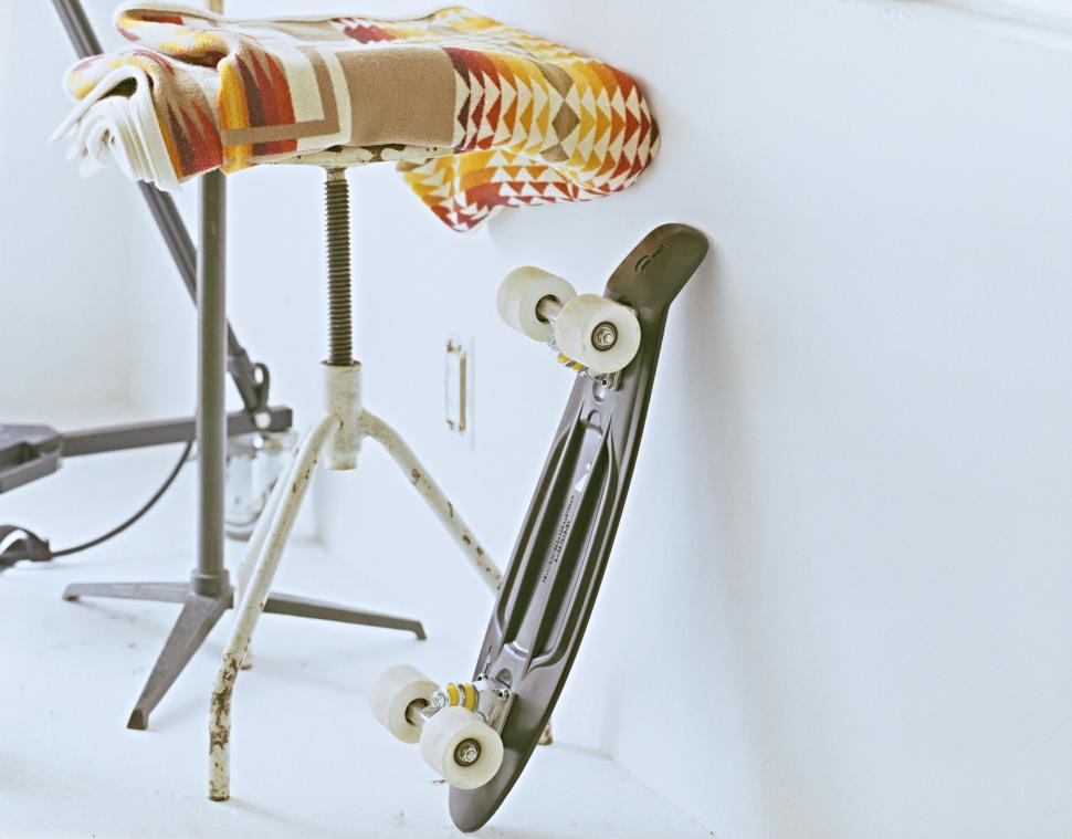 Free Image of Minimalist interior scene with skateboard leaning against a stool 