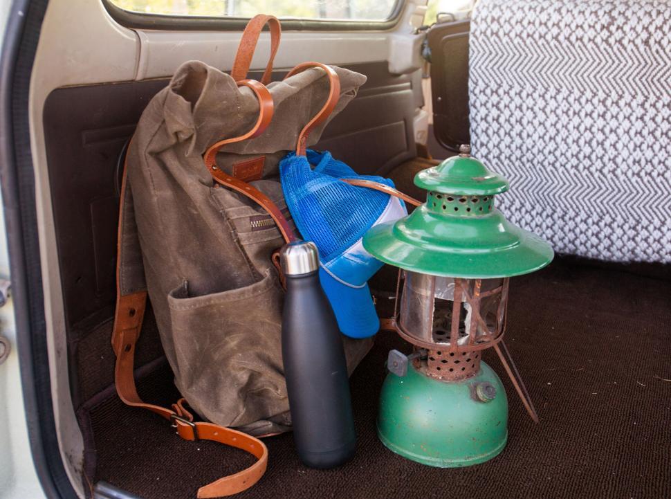 Free Image of Backpack, water bottle, lantern and hat in a vehicle trunk. 