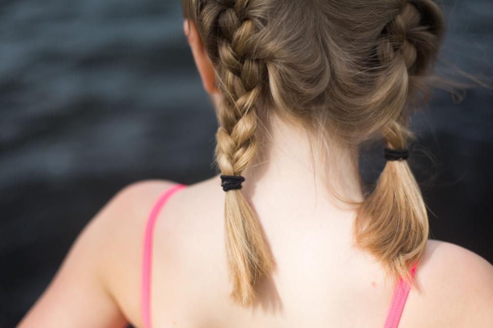 Free Image of Back view of a girl with two braids standing by the water. 