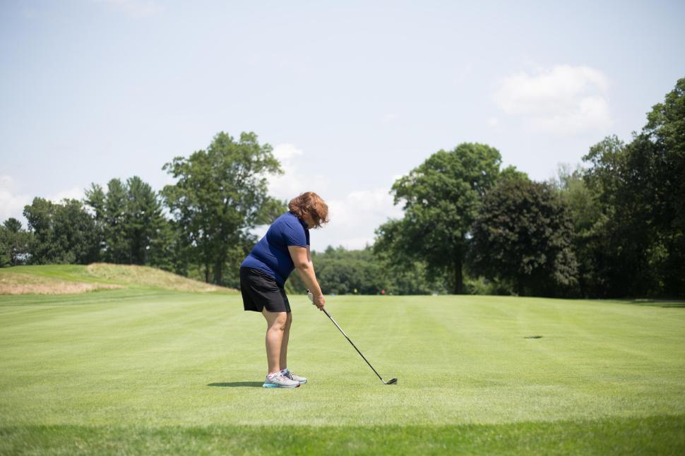 Free Image of Woman playing golf on green field under clear sunny sky 