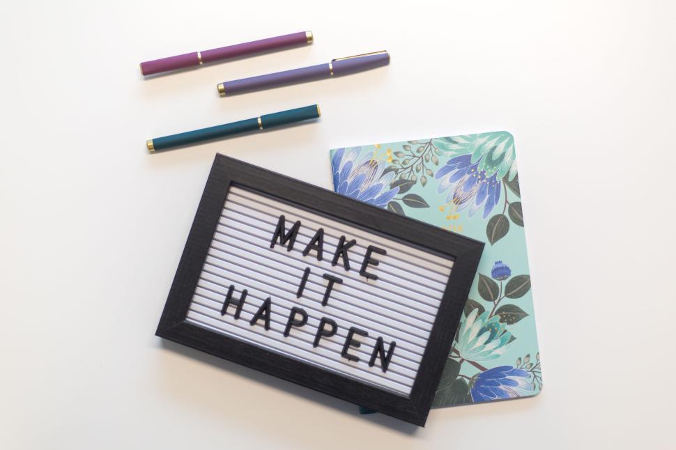 Free Image of Inspirational letterboard sign saying  Make It Happen  on desk. 