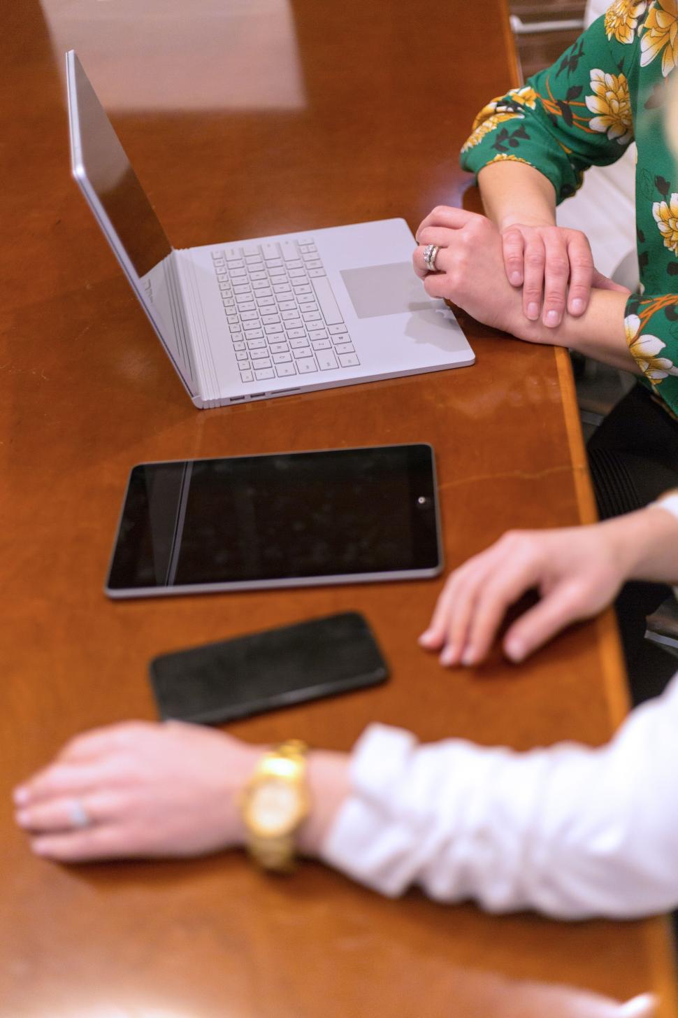 Free Image of Two people working on a laptop, tablet, and smartphone at a desk. 
