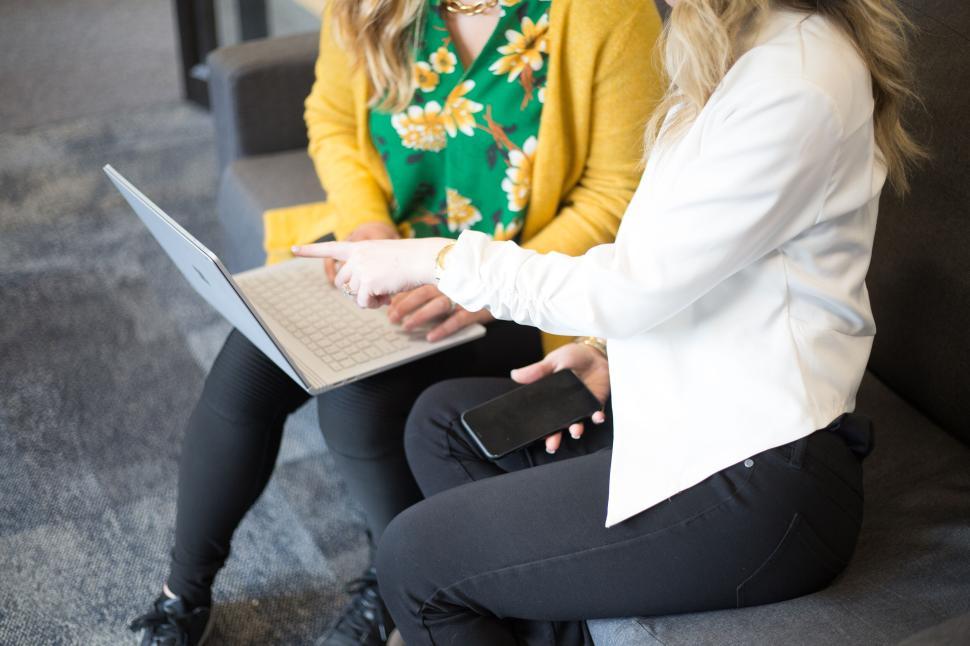 Free Image of Two women in discussion holding laptop in modern office 