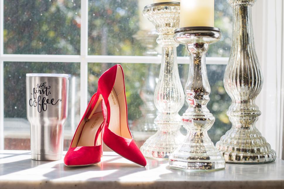 Free Image of Red high heels and coffee travel mug on windowsill with candles 