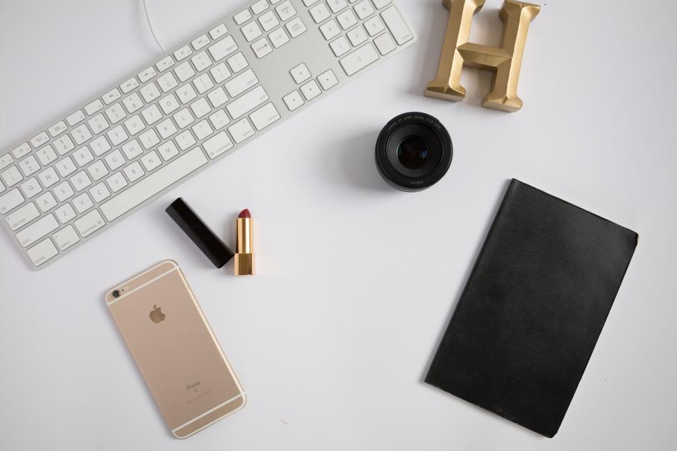Free Image of Desk essentials with keyboard, phone, lipstick, notebook, and lens 