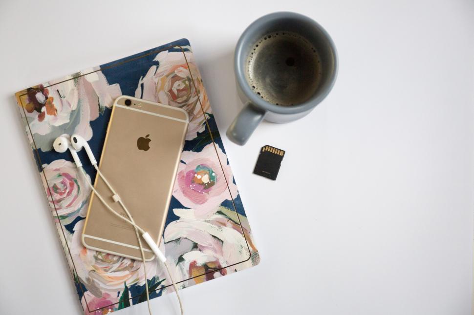 Free Image of Floral notebook with iPhone, earphones, coffee, and memory card 