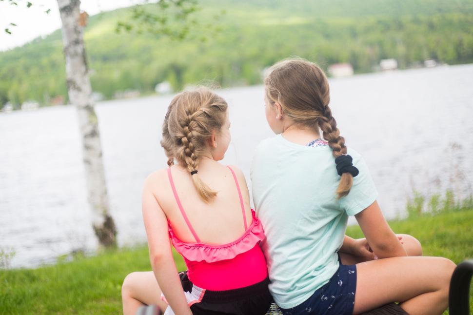 Free Image of Two young girls with braided hair enjoying a lakeside view. 