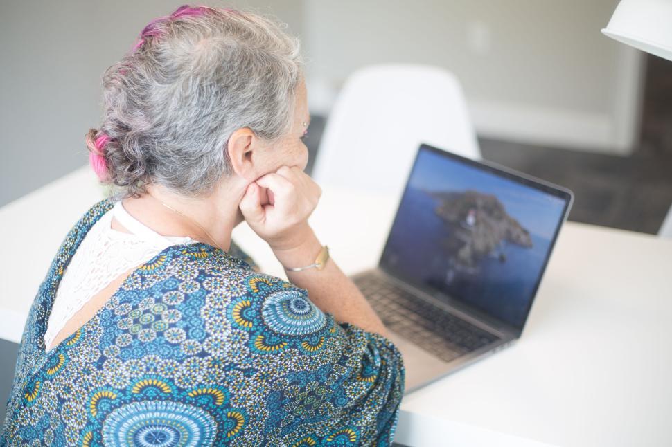 Free Image of Older adult woman using a laptop during a video call, side view. 