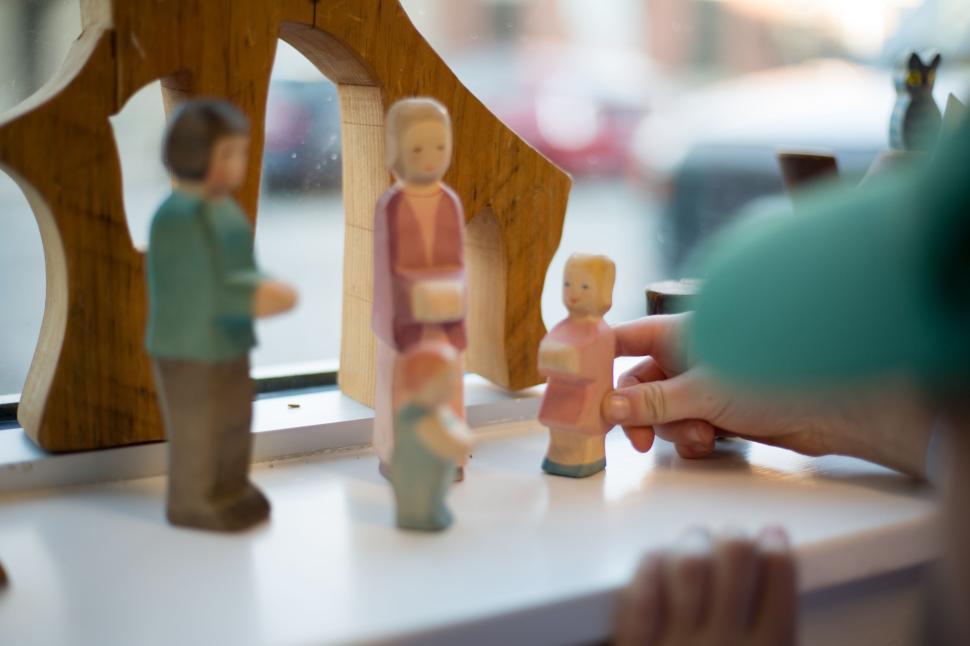 Free Image of Wooden family figurines displayed on a window sill under daylight. 