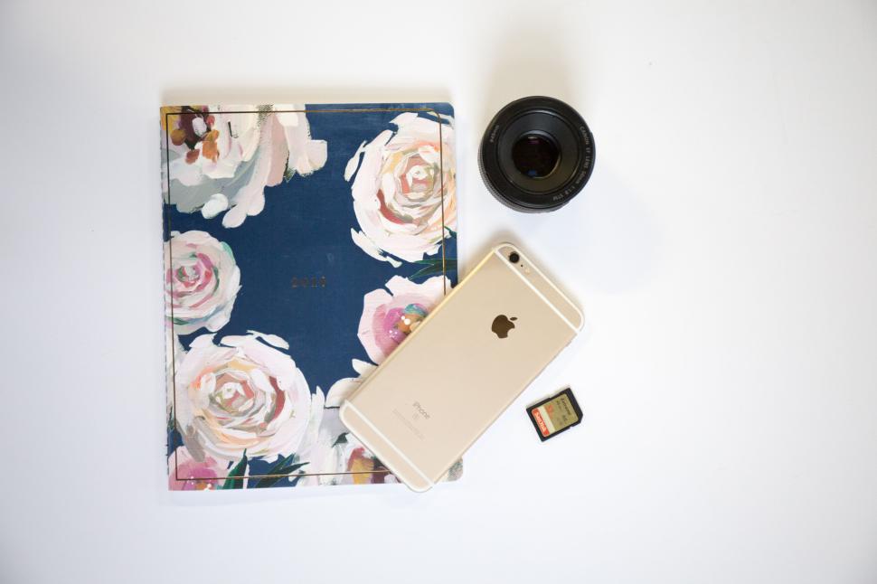 Free Image of Floral planner with iPhone and memory card on a white background. 