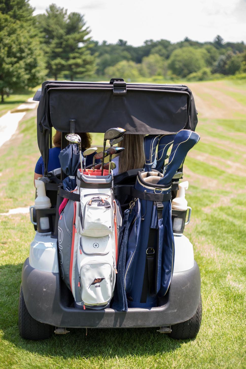 Free Image of Golf cart with golf bags on a green field during a sunny day. 