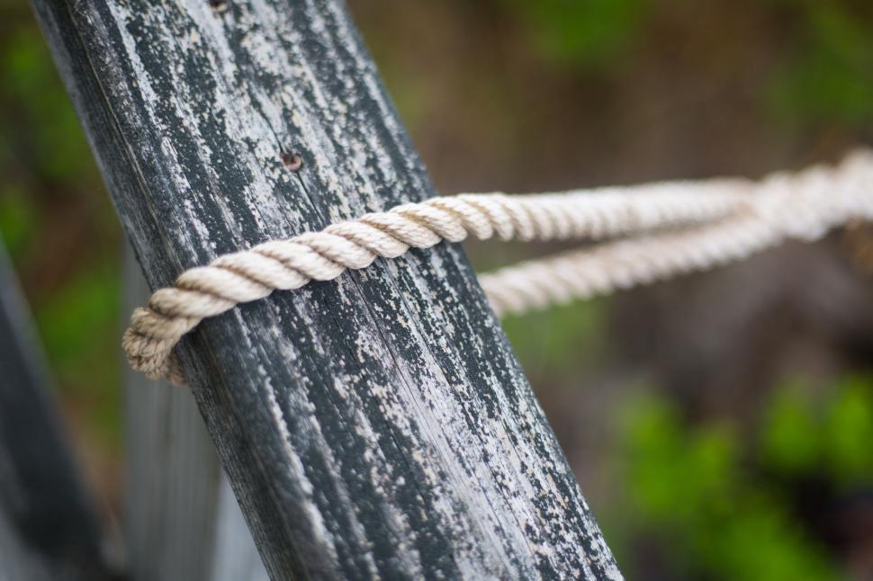 Free Image of Close-up of rope tied around weathered wooden post outdoors. 