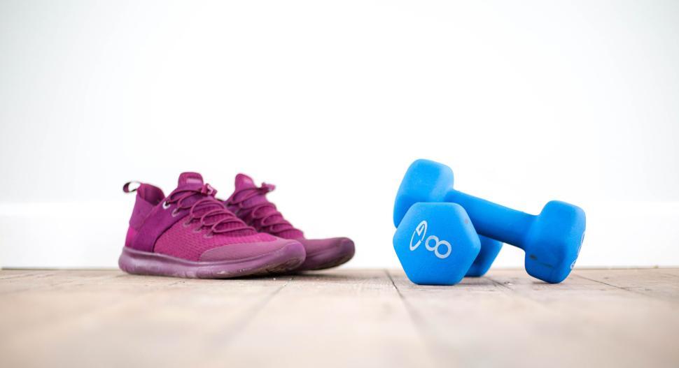 Free Image of Purple sneakers and blue dumbbell on a wooden floor indoors. 