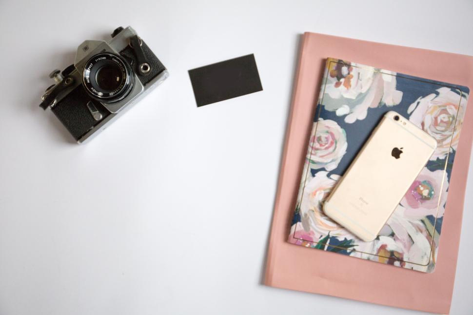 Free Image of Vintage camera and modern essentials on a clean white backdrop. 