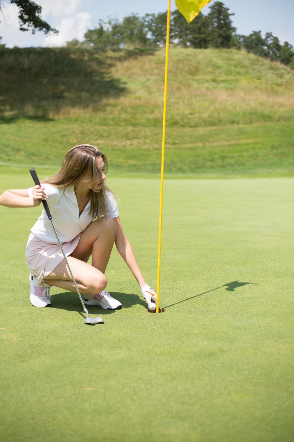 Free Image of Golfer marking her position on a sunny day on the green. 